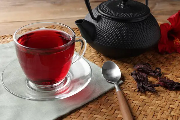 Cam fincanda lezzetli amber çayı, çaydanlık, kuru roselle sepals ve tahta masada kaşık, yakın çekim.