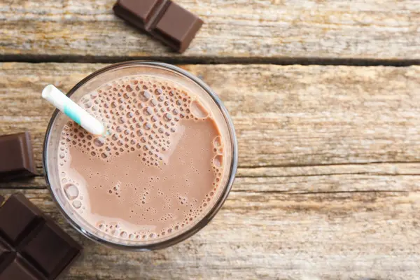 Bardakta çikolatalı süt ve ahşap masada parçalar, düz bir şekilde. Metin için boşluk