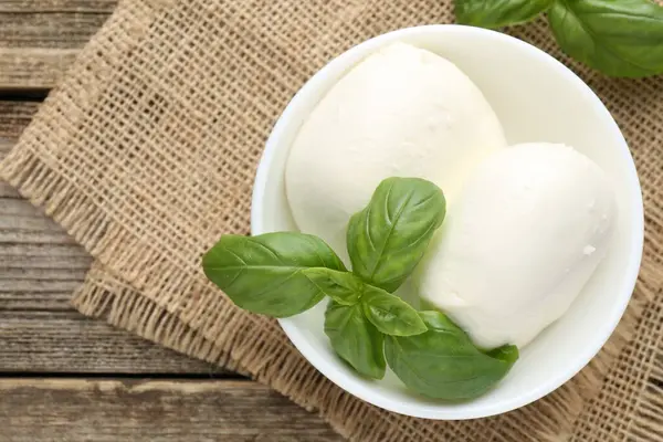 Ahşap masada lezzetli mozzarella peyniri ve fesleğen.