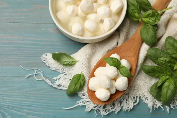Mozzarella peyniri topları ve fesleğen mavi ahşap masada, düz yatıyordu.