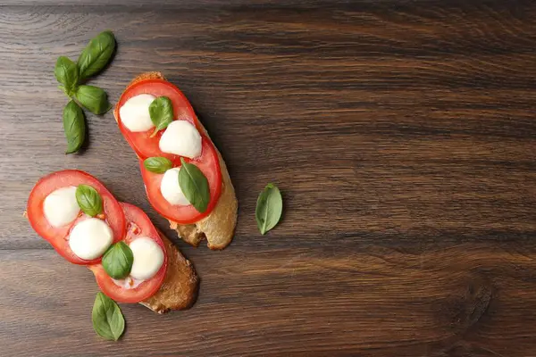 Peynirli, domatesli, ahşap masadaki fesleğenli lezzetli sandviçler. Metin için boşluk