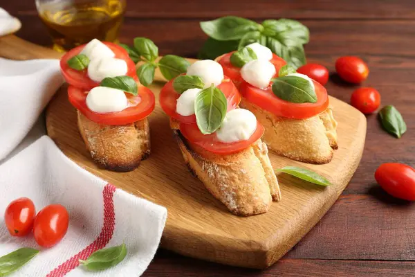Mozarella peynirli, domatesli ve ahşap masadaki fesleğenli lezzetli sandviçler.