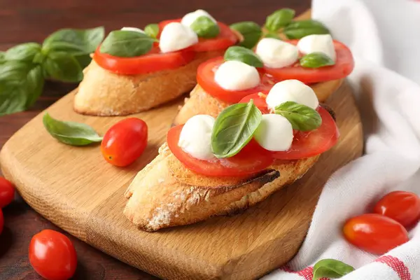 Mozarella peynirli, domatesli ve ahşap masadaki fesleğenli lezzetli sandviçler.