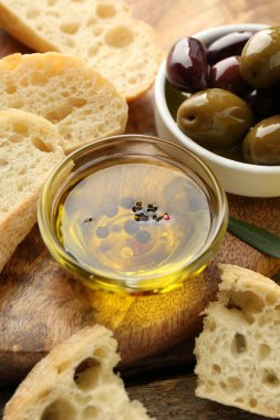 Yağlı ekmek dilimleri, ahşap masada baharatlar ve zeytinler, yakın plan.