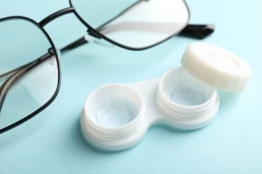 Açık turkuaz arka planda kontak lensler ve gözlükler, yakın plan