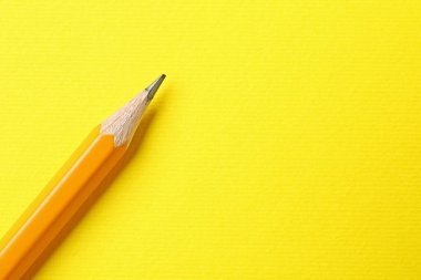 Sarı arka planda keskin bir grafit kalem, üst manzara. Metin için boşluk
