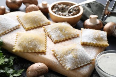 Pişmemiş ravioli ve mantarlar siyah masada, yakın plan.