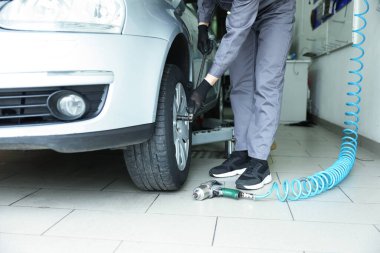 Tamirci araba servisinde lastik değiştiriyor, yakın plan.