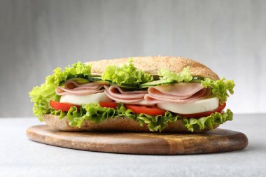 Jambonlu ve sebzeli baget sandviç açık gri masada, yakın plan.