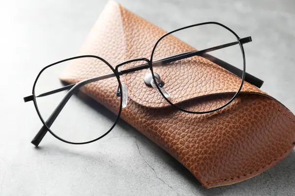 Gri masada şık gözlükleri olan bir çanta, yakın plan.