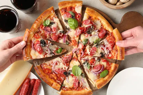 Işık masasında ince tütsülenmiş sosisle lezzetli bir pizza yiyen bir kadın.