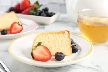 Lezzetli kek parçaları, böğürtlenli ve beyaz mermer masada çay, yakın plan.