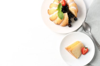 Pudra şekeri, böğürtlen, nane ve kaşıkla beyaz masada, düz bir şekilde. Metin için boşluk