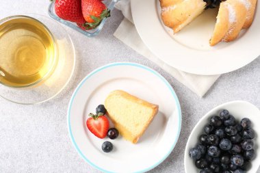 Pudra şekeri, böğürtlen ve çay ile açık gri masada, düz bir şekilde yatıyordu.