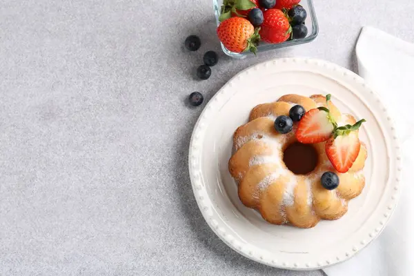 Açık gri masada pudra şekeri ve böğürtlenli leziz bir kek. Metin için boşluk