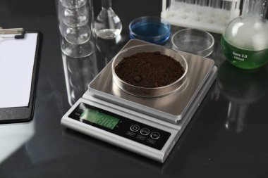 Siyah ayna masasındaki Petri kabı ve diğer laboratuvar camlarıyla ölçeklendir, yakın plan.