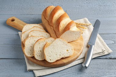 Gri ahşap masada dilimlenmiş ekmek ve bıçak