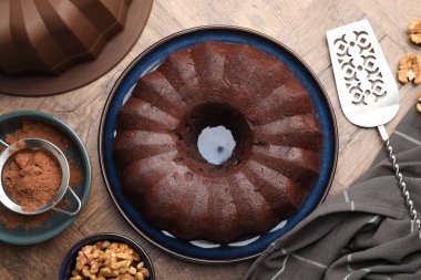 Lezzetli çikolatalı kek, ceviz ve kakao tozu ahşap masada, düz uzanmış