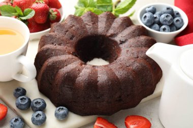 Lezzetli çikolatalı kek, çay ve böğürtlen ışık masasında, yakın plan.