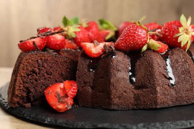 Çilekli lezzetli çikolatalı kek, ahşap masada, yakın plan.