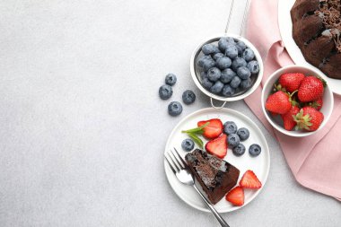 Açık gri desenli masada çilekli ve yaban mersinli nefis çikolatalı kek. Metin için boşluk