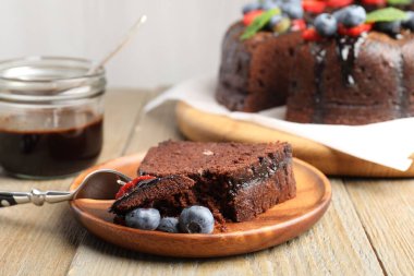 Bir parça lezzetli çikolatalı kek, ahşap masada yaban mersini, yakın plan.