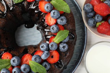 Hafif ahşap masada çilekli, nane ve böğürtlenli lezzetli çikolatalı kek.