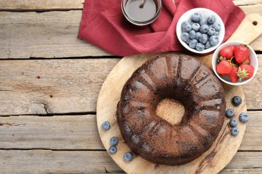 Lezzetli çikolatalı kek, ahşap masada çilek ve yaban mersini, düz yatak. Metin için boşluk