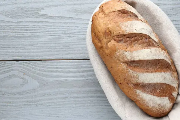 Gri ahşap masada, sepetin içinde bir somun ekmek, üst manzara. Metin için boşluk