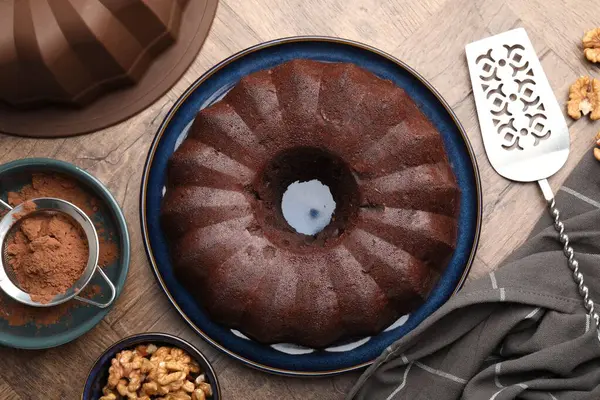 Lezzetli çikolatalı kek, ceviz ve kakao tozu ahşap masada, düz uzanmış