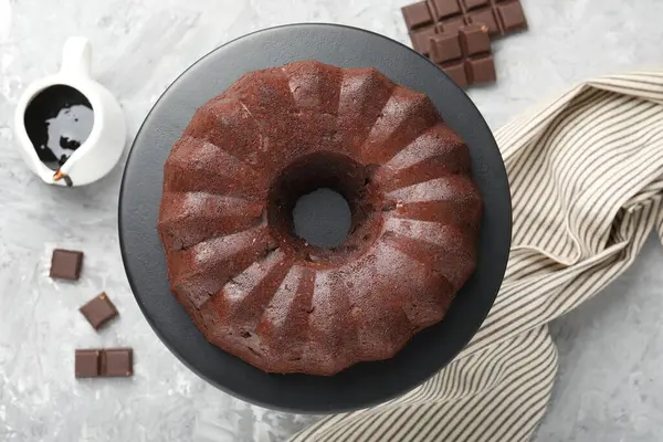 Lezzetli kek, çikolata ve sos parçaları gri masada, düz uzanmış.