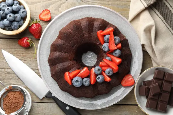 Lezzetli çikolatalı kek, böğürtlenli ve bıçaklı, ahşap masa, düz.