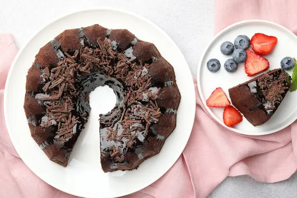 Açık gri desenli masada çilekli ve yaban mersinli lezzetli çikolatalı kek, düz konum.