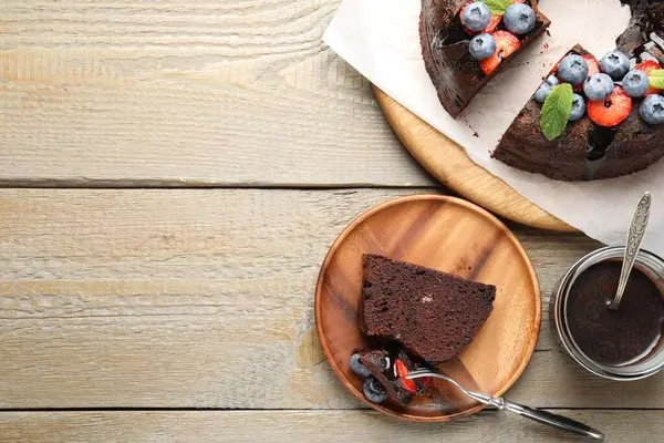 Çilekli, nane ve böğürtlenli, ahşap masada servis edilen lezzetli çikolatalı kek. Metin için boşluk