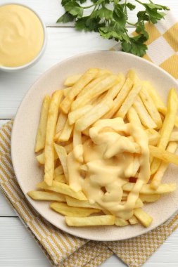 Peynir soslu patates kızartması ve beyaz ahşap masada maydanoz.