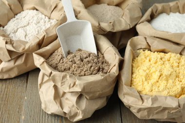 Tahta masadaki kağıt torbalarda farklı türde un, yakın plan.