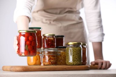 Farklı turşulu ürünlerle dolu kavanozları olan kadın arka planda ışığa karşı, yakın plan.