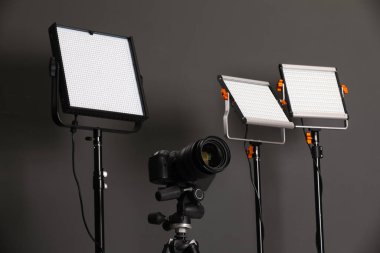 Profesyonel ışıklandırma ekipmanı ve gri arka planda kamera.