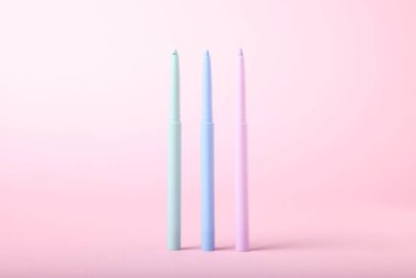 Pembe arka planda renkli göz kalemleri, yakın plan.