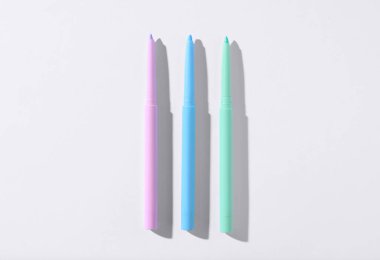 Beyaz arka planda renkli göz kalemleri, düz yatış