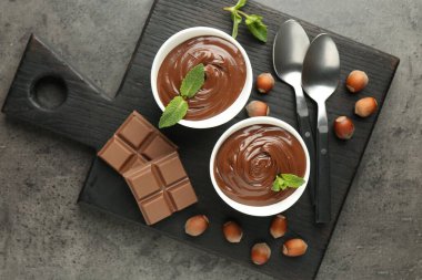 Lezzetli çikolata, parçalar, nane ve fındık, gri desenli masa, üst manzara.