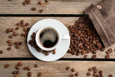 Aromatik kahve fincanda ve fasulye ahşap masada, düz yerde.