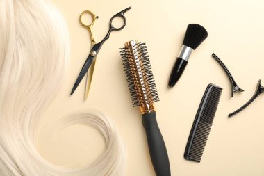 Saç tokası ve bej arka planda farklı kuaför aletleri.