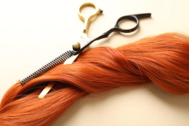 Bej arkaplanda saç tokası ve makas, yakın plan.