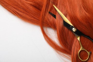 Işık arkaplan üzerinde saç teli ve makas, üst görüş. Metin için boşluk