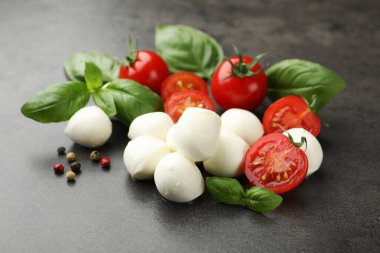 Mozzarella peyniri, domates, fesleğen ve biberler gri masada, yakın plan.