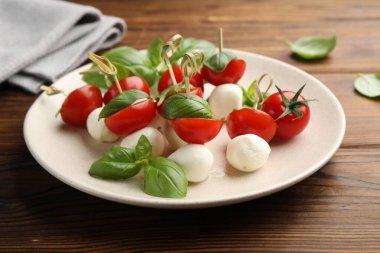 Ahşap masada mozarella, domates ve fesleğen ile aperatifler, yakın plan.