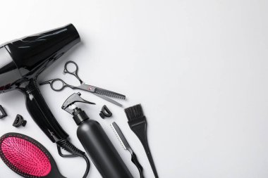 Açık gri arka planda farklı kuaför aletleri, düz yatış. Metin için boşluk