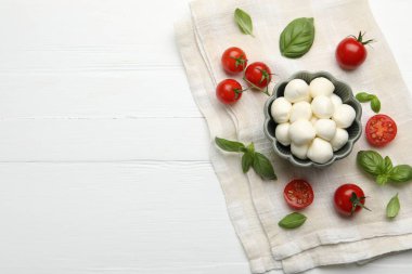 Lezzetli mozzarella peyniri topları, domates ve fesleğen beyaz ahşap masa, düz yatak. Metin için boşluk