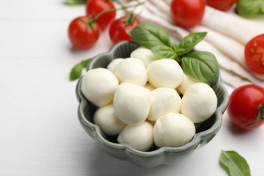 Lezzetli mozzarella peynir topları, domates ve fesleğen beyaz ahşap masada, yakın plan.